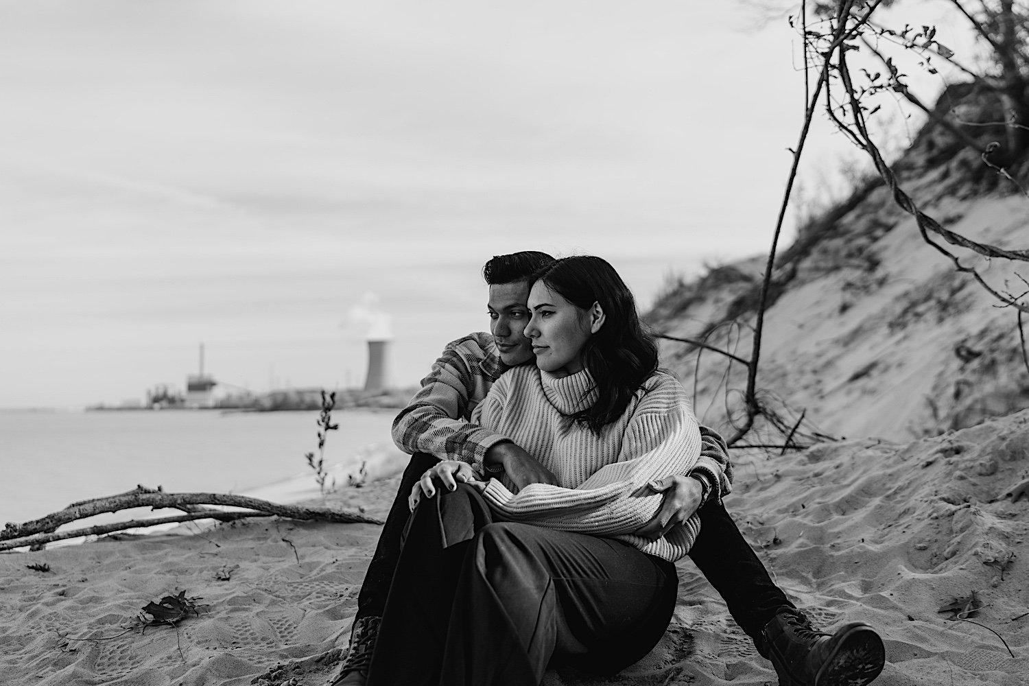 Couple sit and look out over water at Indiana Dunes anniversary session