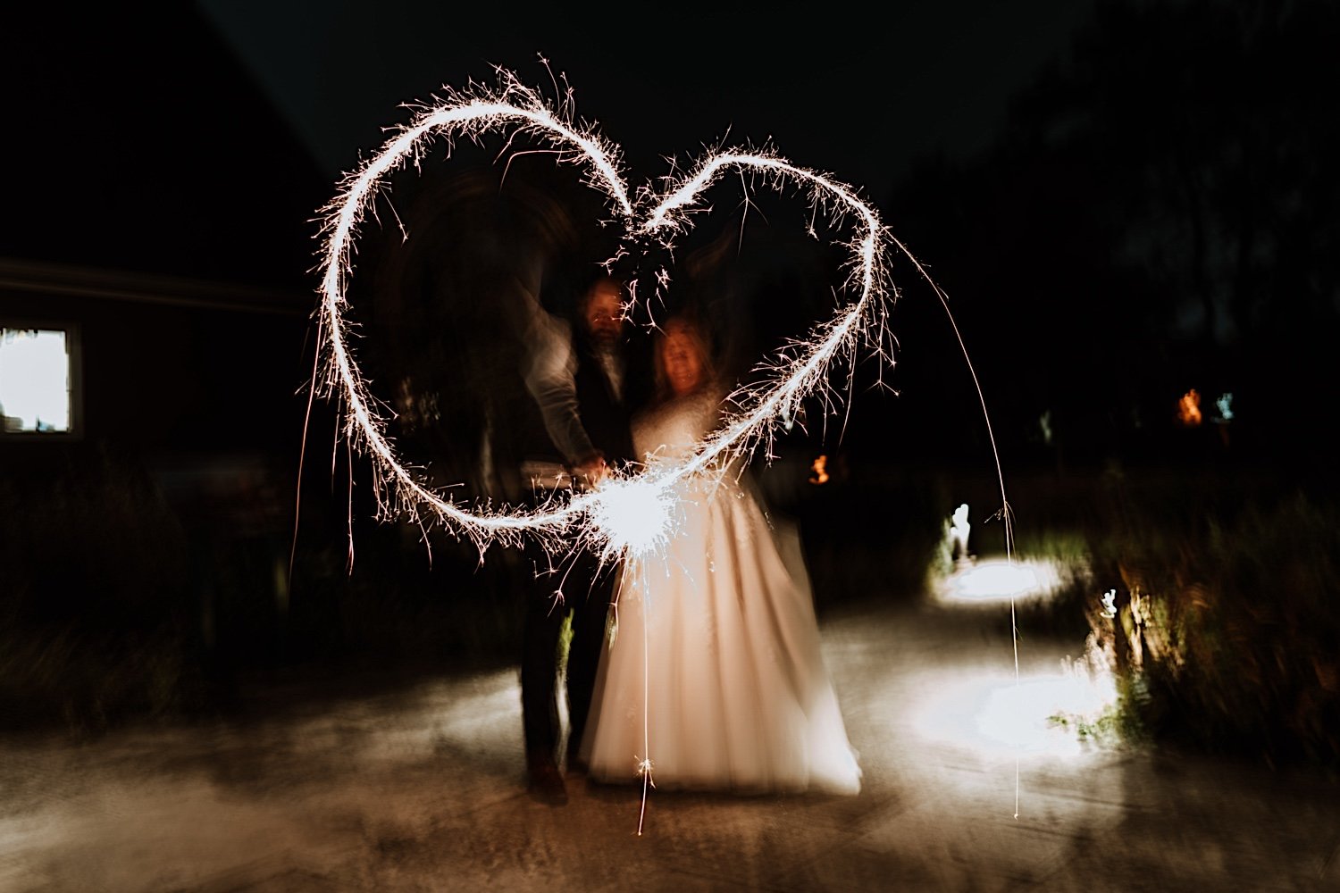 Bride and groom make a heart with sparklers to cap off Lake Ellyn Boathouse wedding