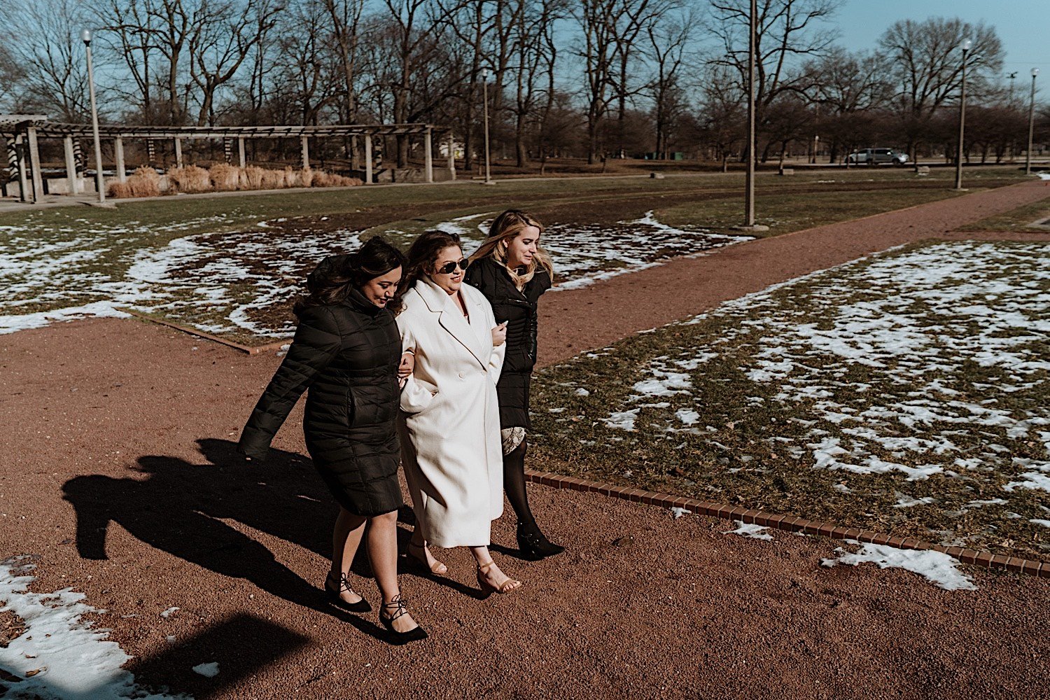 Bride walking in a park with her two bridesmaids accompanying her