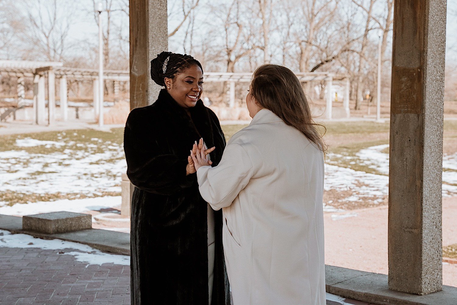 Brides hold hands during their first look in Humboldt Park