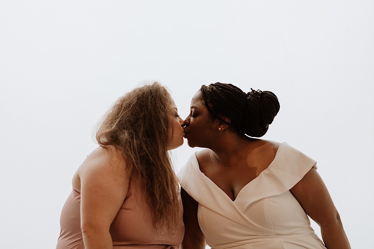 Brides kiss after their Humboldt Park wedding with white background