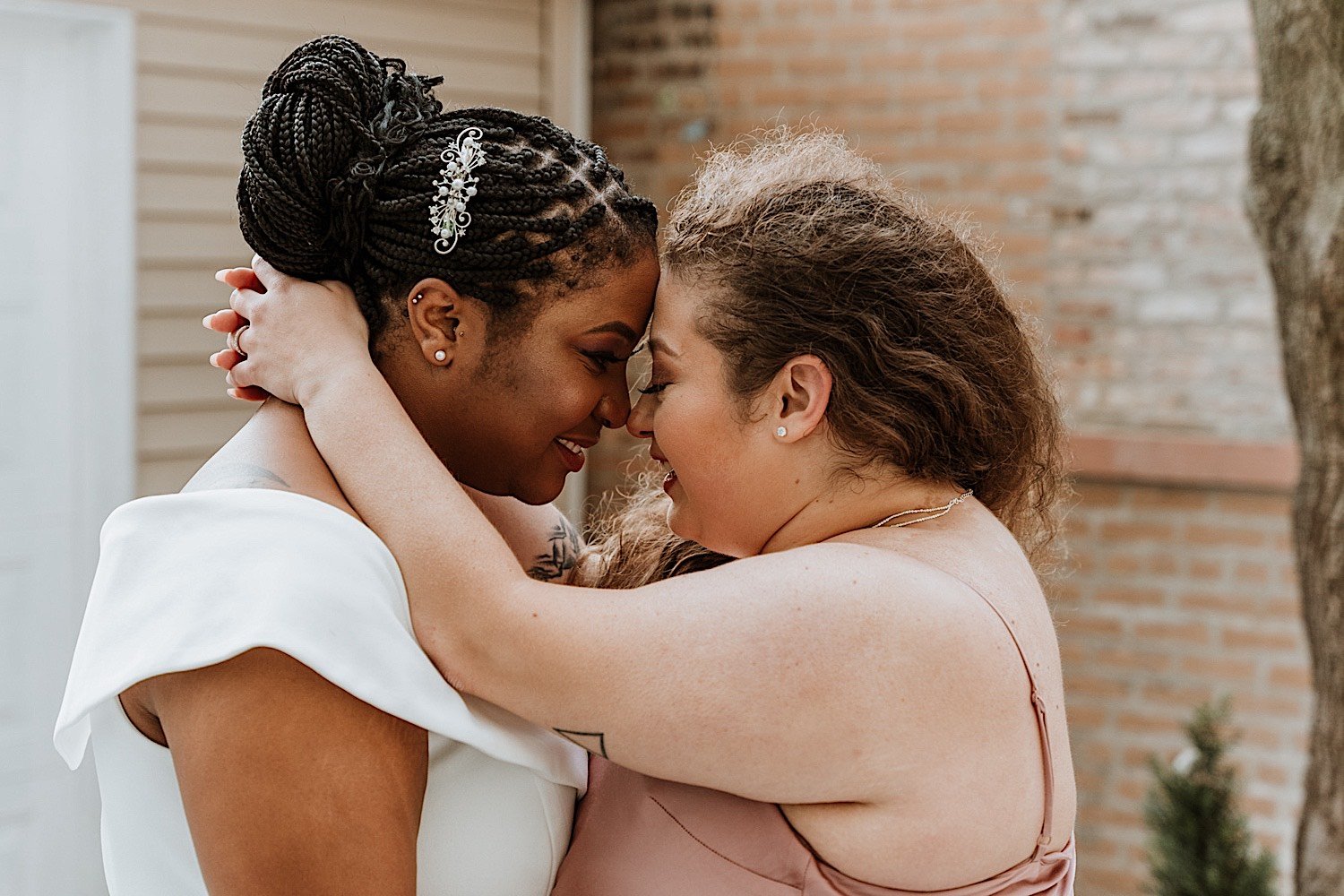 Newlywed brides laugh and embrace each other in Humboldt Park Chicago after their wedding