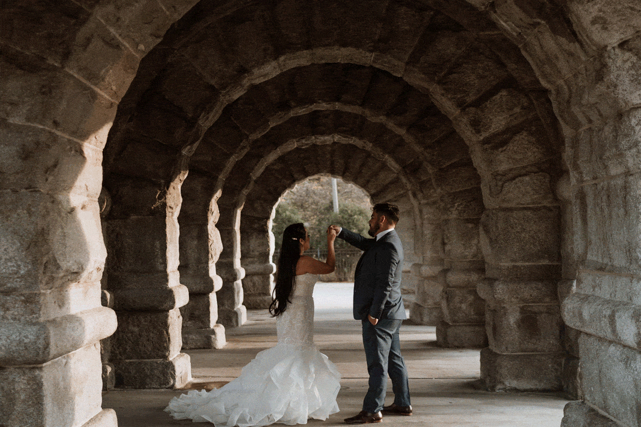 gif of a husband spinning his bride underneath stone archways