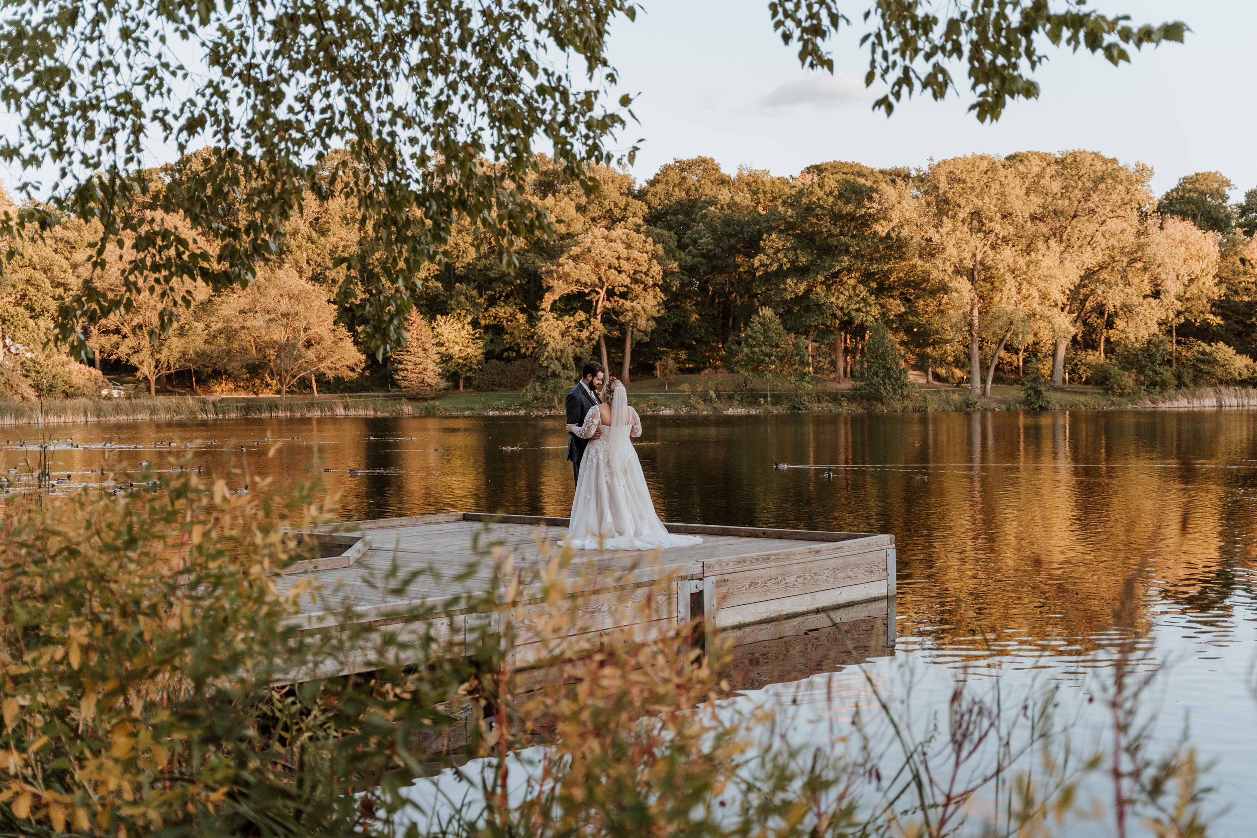 Couple share first dance together on a wooden dock on the lake