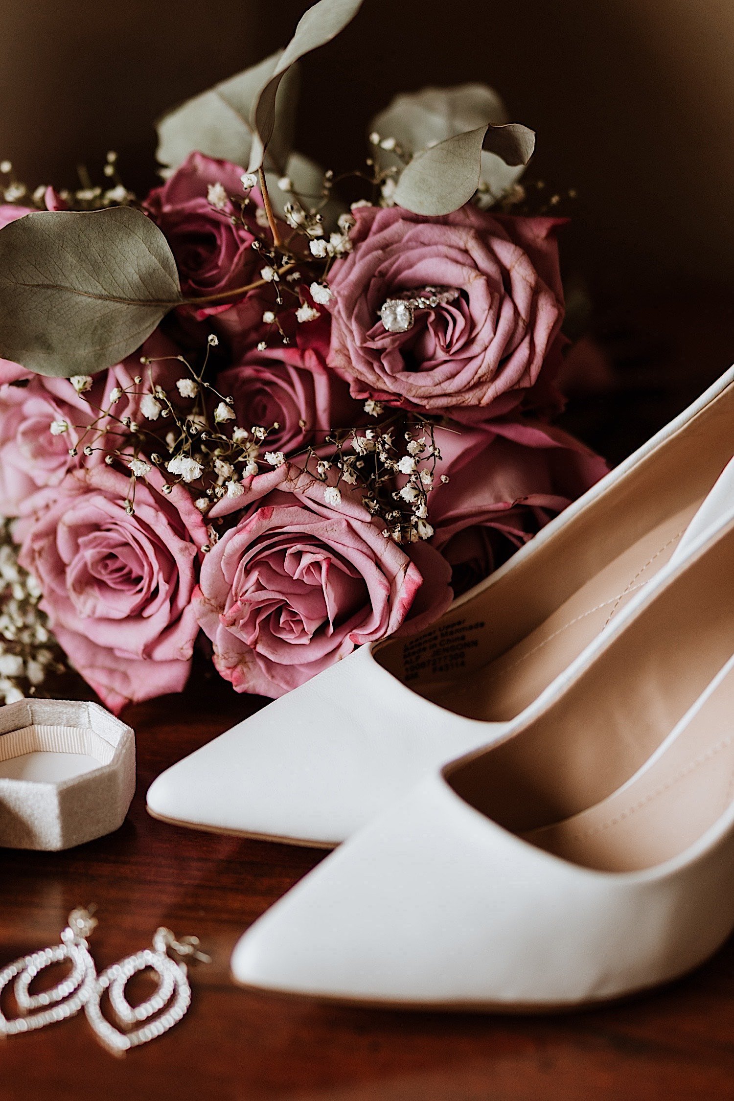 Shoes, earrings and flowers on a wood table