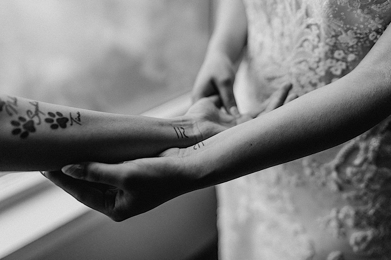 Black and white photo of a close up of a bride and her sisters matching tattoos on their wrists
