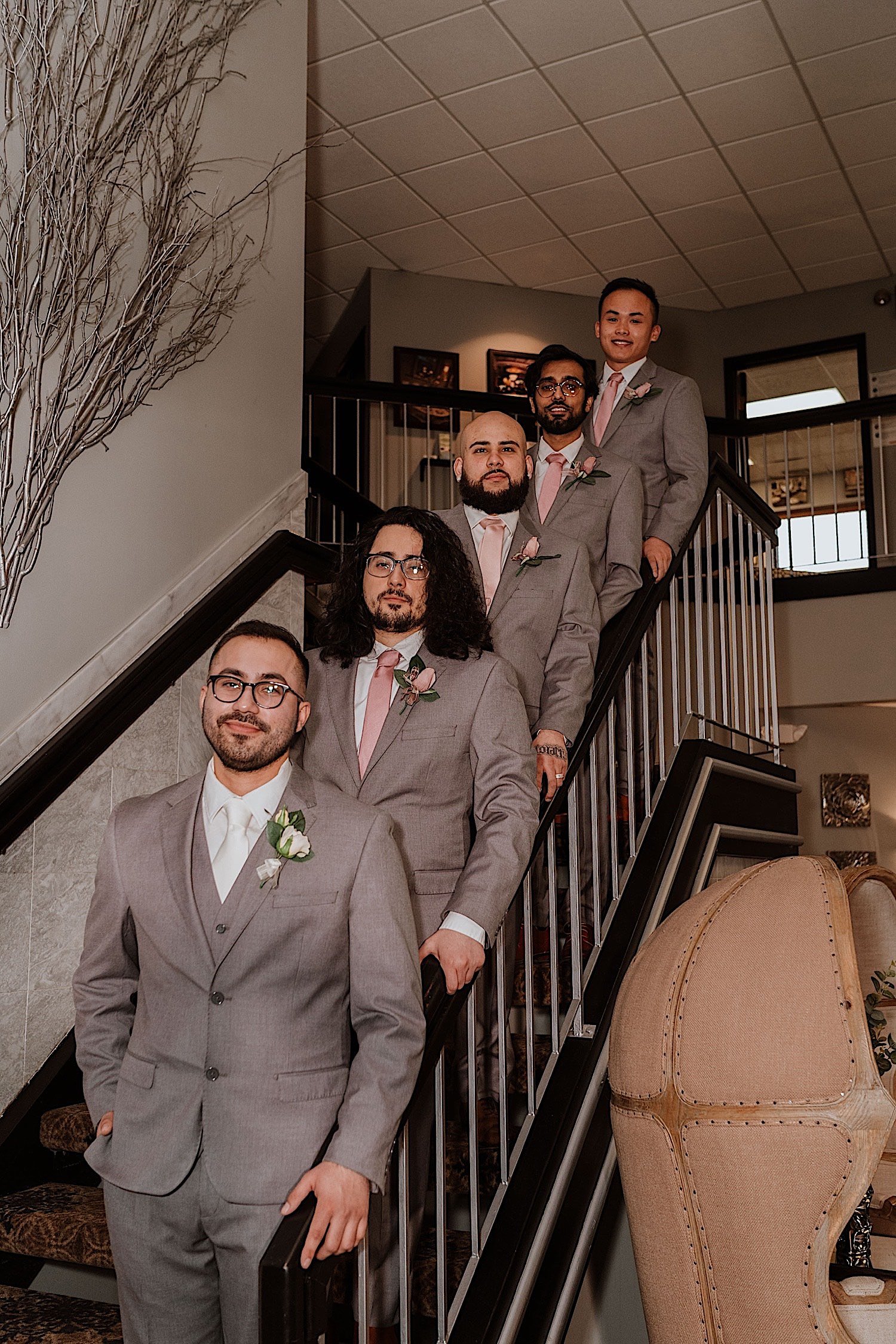 Groom and groomsmen line up on railing of staircase