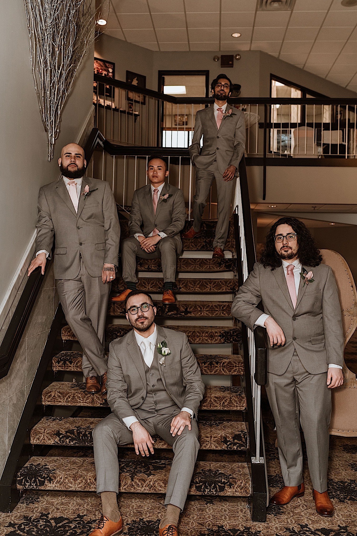 Groom poses on a staircase with his groomsmen around him
