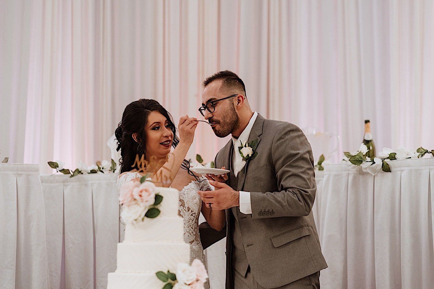 Bride feeds groom a piece of cake during their wedding reception