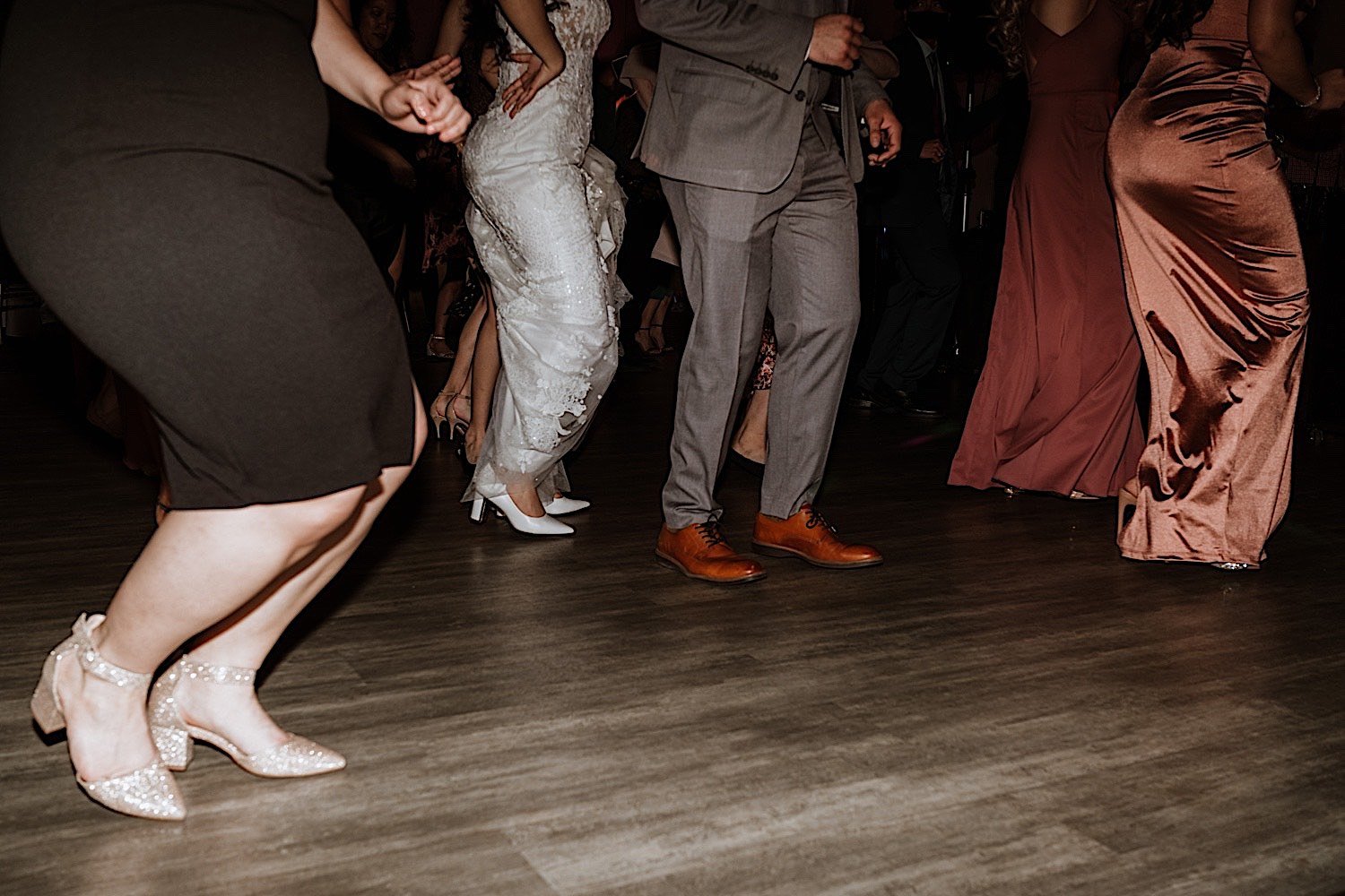 Legs of bride and groom as well as guests dancing during wedding reception