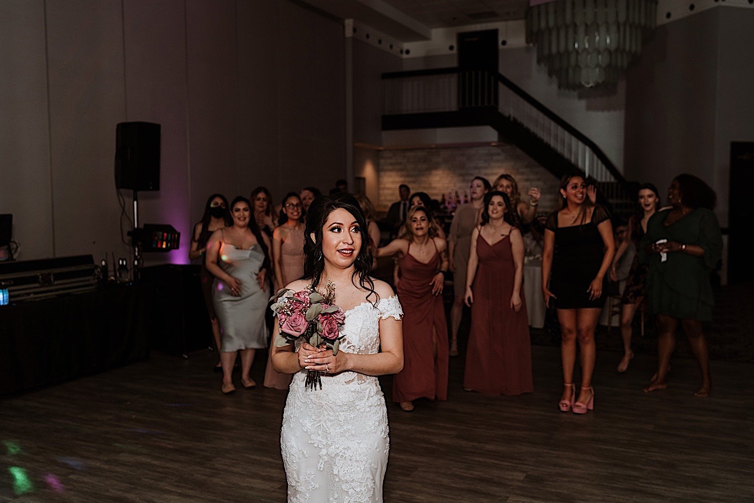 Bride prepares to toss the bouquet to guests standing behind her during Chicagoland ballroom wedding reception
