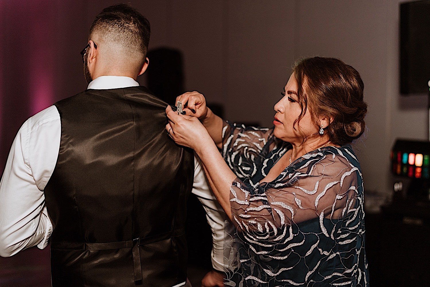 Mother fixes grooms vest on dance floor during wedding reception