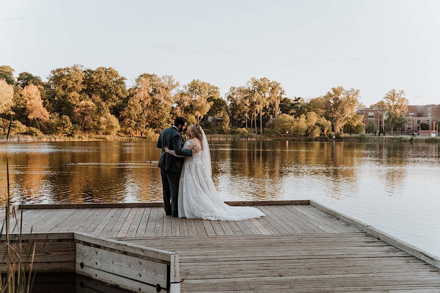 Bride and groom hold one another on dock overlooking the water