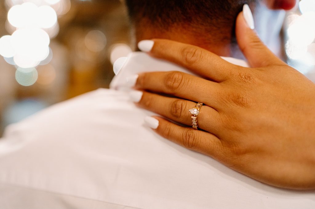 A future bride shows off her engagement ring during their engagement session.  It is a pear cut ring with diamonds along the wedding band.
