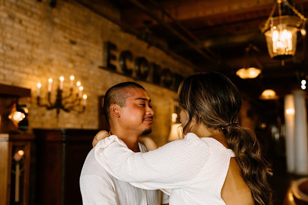 A couple holds each other close while looking into each others eyes during their engagement session at Salvage One in Chicago Illinois.