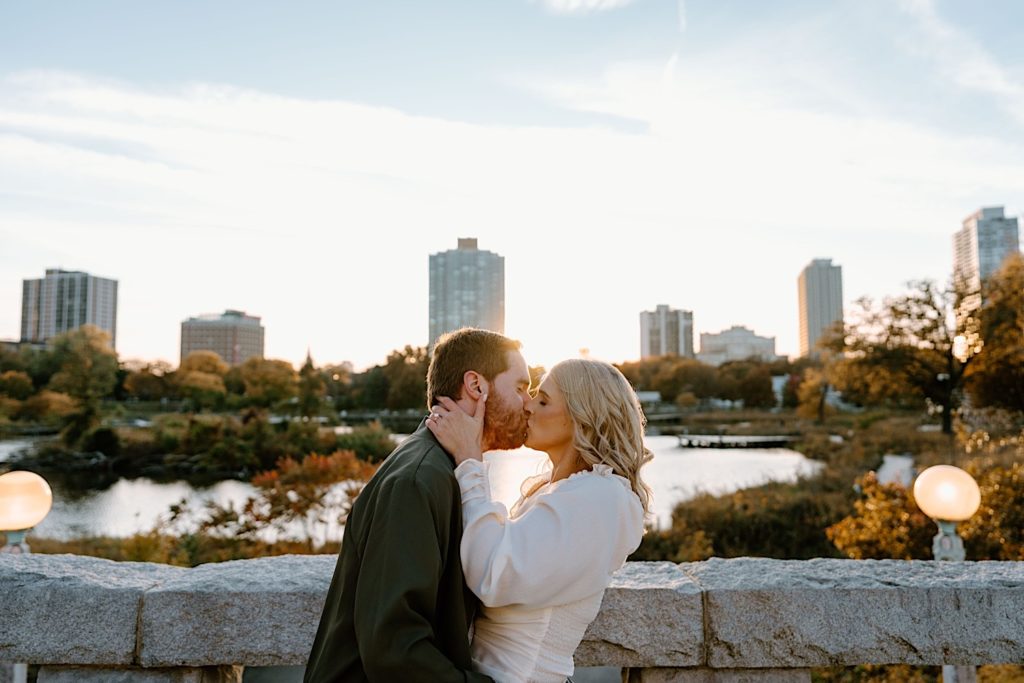 An engaged couple kisses on a bridge in Lincoln Park in Chicago during golden hour.