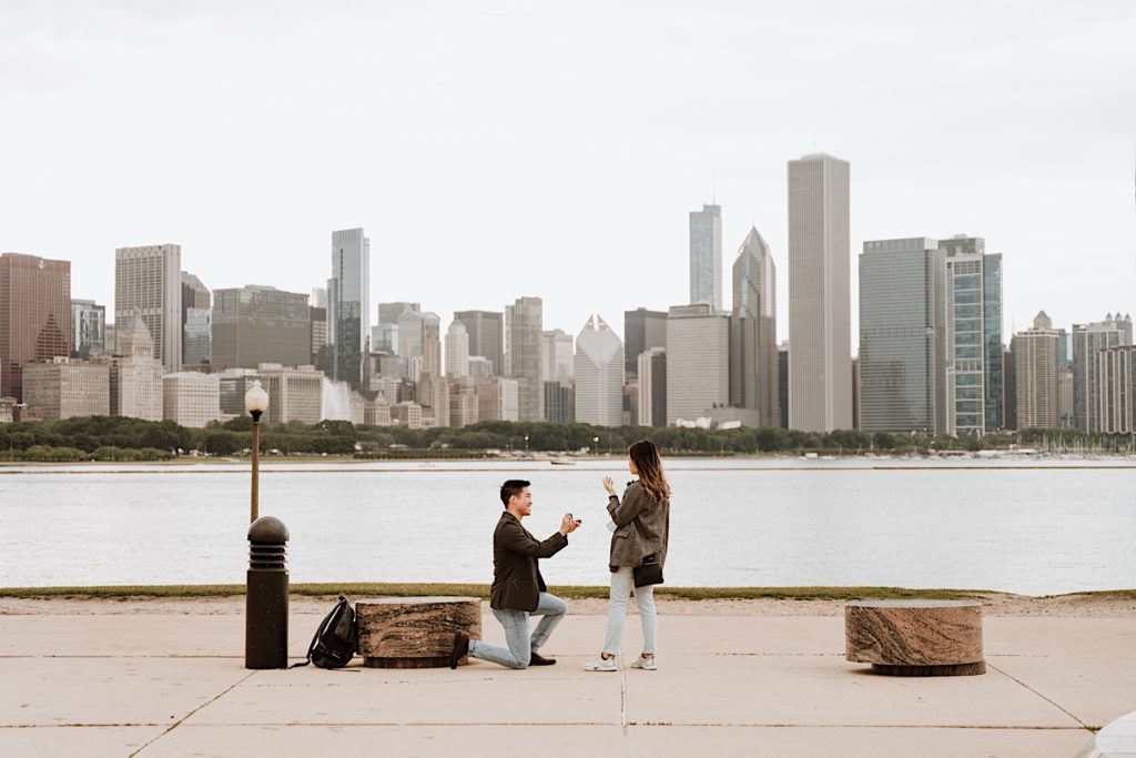A man proposes to his girlfriend on museum campus in Chicago illinois.