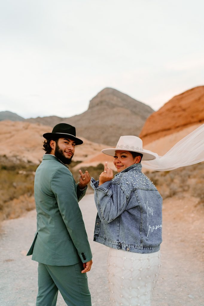 The bride and groom show off their wedding rings for the camera with their backs to the camera during their Nevada Elopement