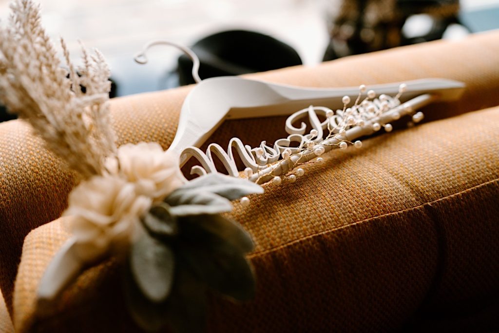A decorated wooden hanger with the brides last name on the hanger.