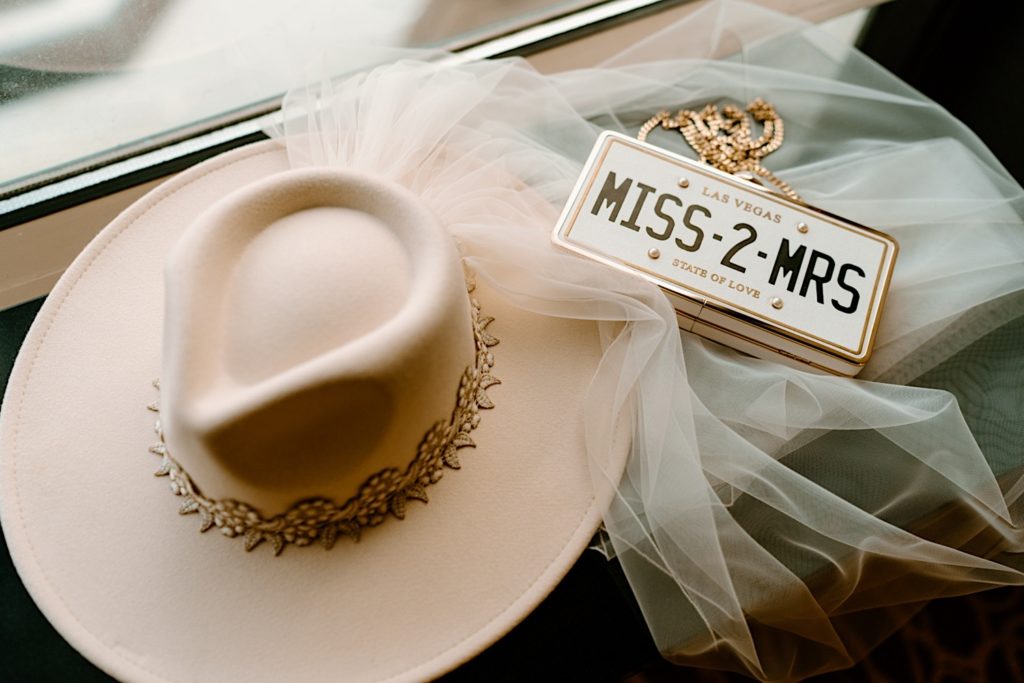 A license plate Miss-2-Mrs purse and a wide brim hat with a veil attached to it.  