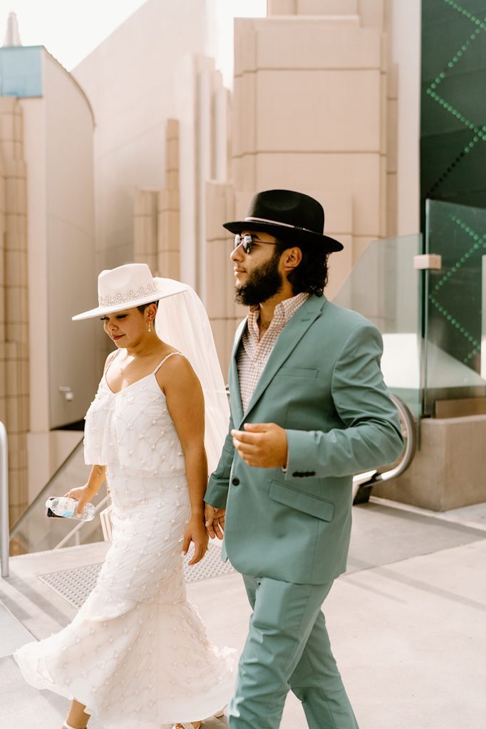 The bride and groom walk over the skyway in Las Vegas together holding hands.