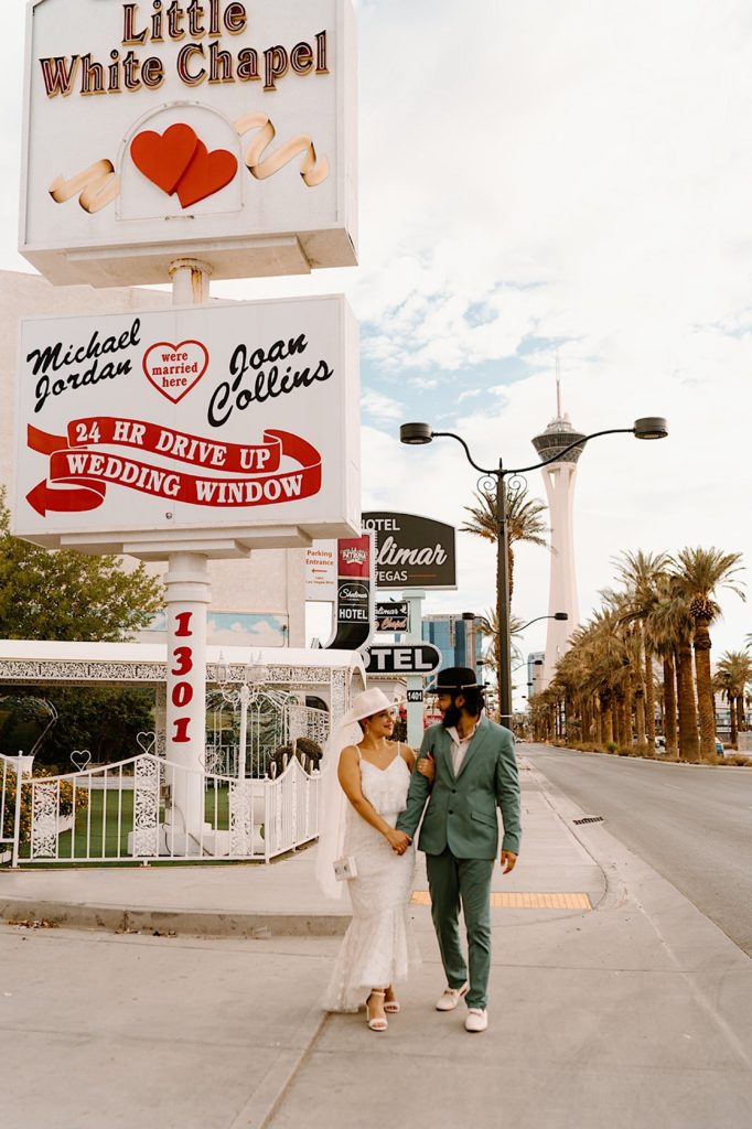 A bride and groom walk through Las Vegas in front of the Little White Chapel before their elopement.