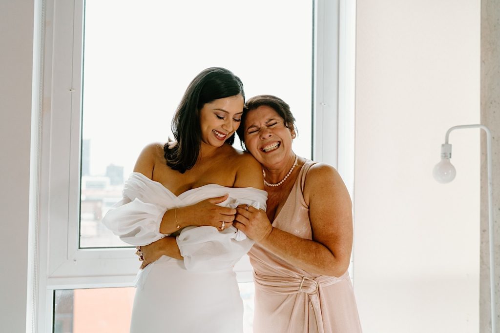 A bride holds her mom and celebrates her wedding morning in their Chicago Airbnb.