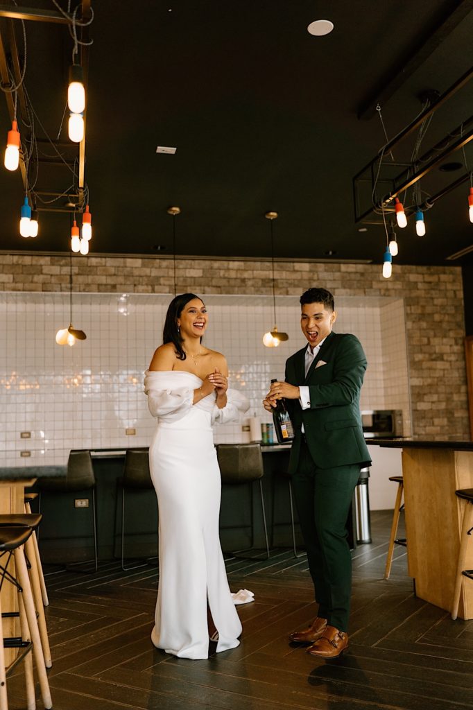 A bride and groom pop champagne to celebrate their wedding day in their Chicago Airbnb.