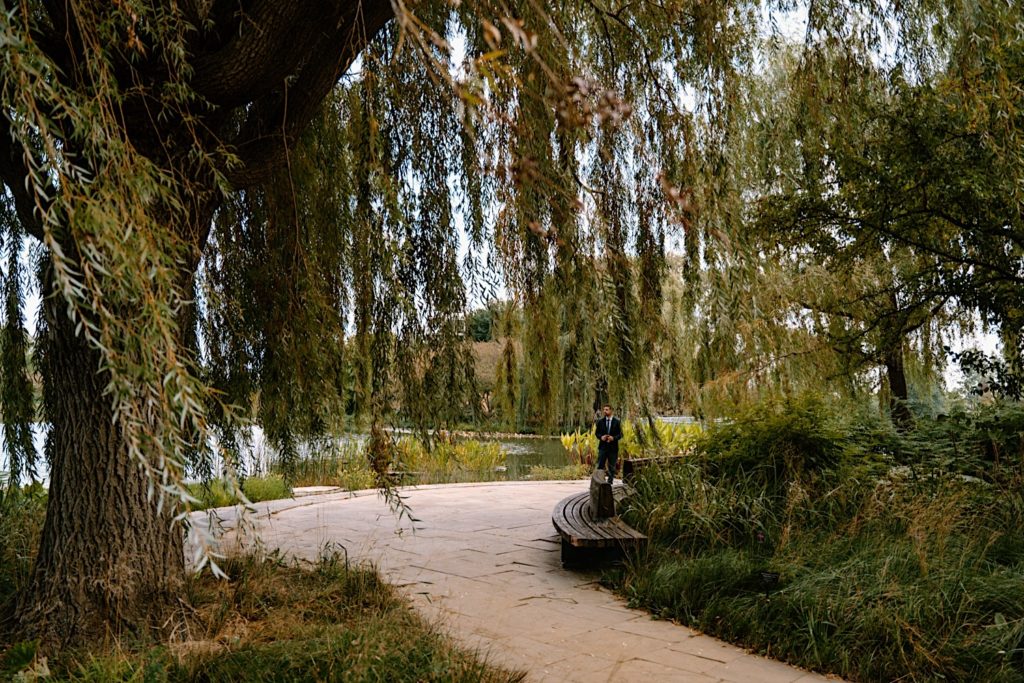 A fiancé stands waiting for his future bride near the pond at the Chicago Botanic Gardens before he proposes

