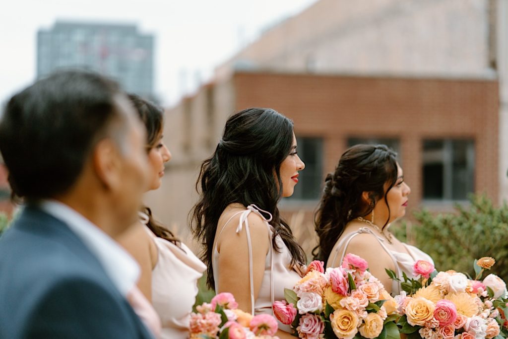 the bridal party watching their best friend get married on the rooftop ceremony space at Loft Lucia.