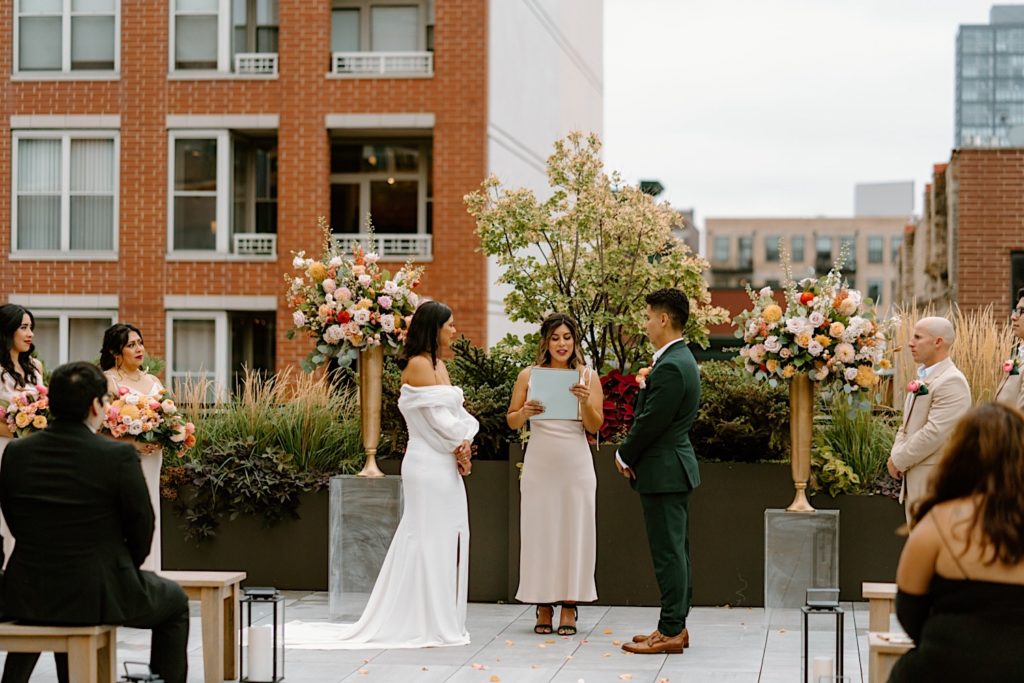 The bride and groom standing during their ceremony at Loft Lucia looking at one another.  
