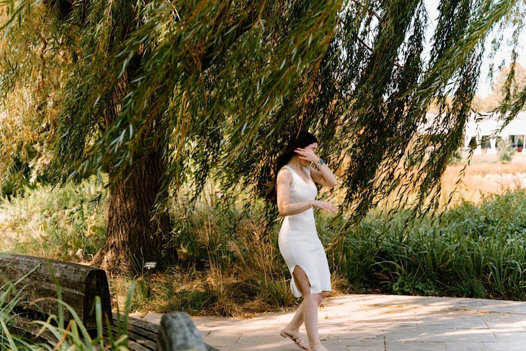 His bride Yesi sees him in the distance as he waits to propose to her on a stone path at the Chicago Botanic Garden.