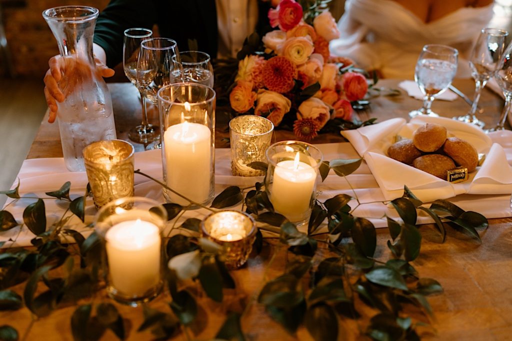 Candles and gold accents with greenery covering the tables at Loft Lucia for a wedding reception.