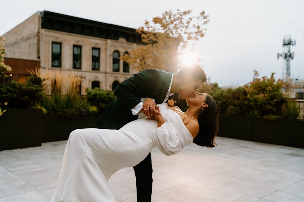 The groom dips his bride while kissing during golden hour before their wedding reception at Loft Lucia in the city of Chicago.