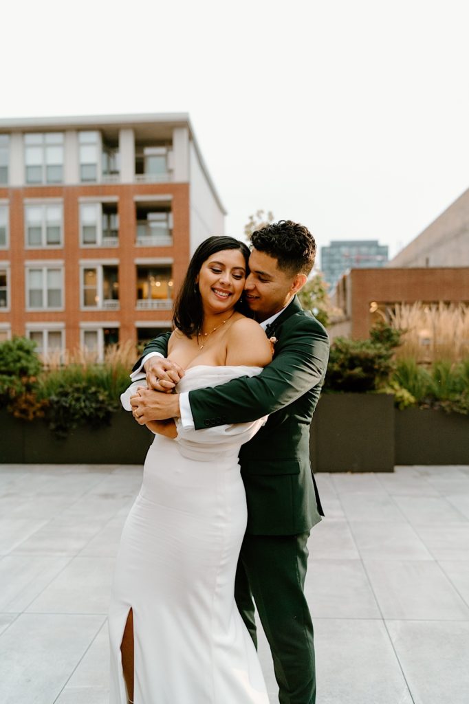 The bride and groom hold one another outside at their rooftop wedding venue.