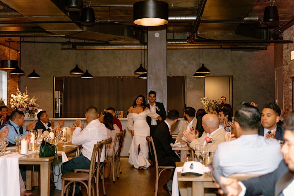 A bride and groom enter their reception at Loft Lucia.