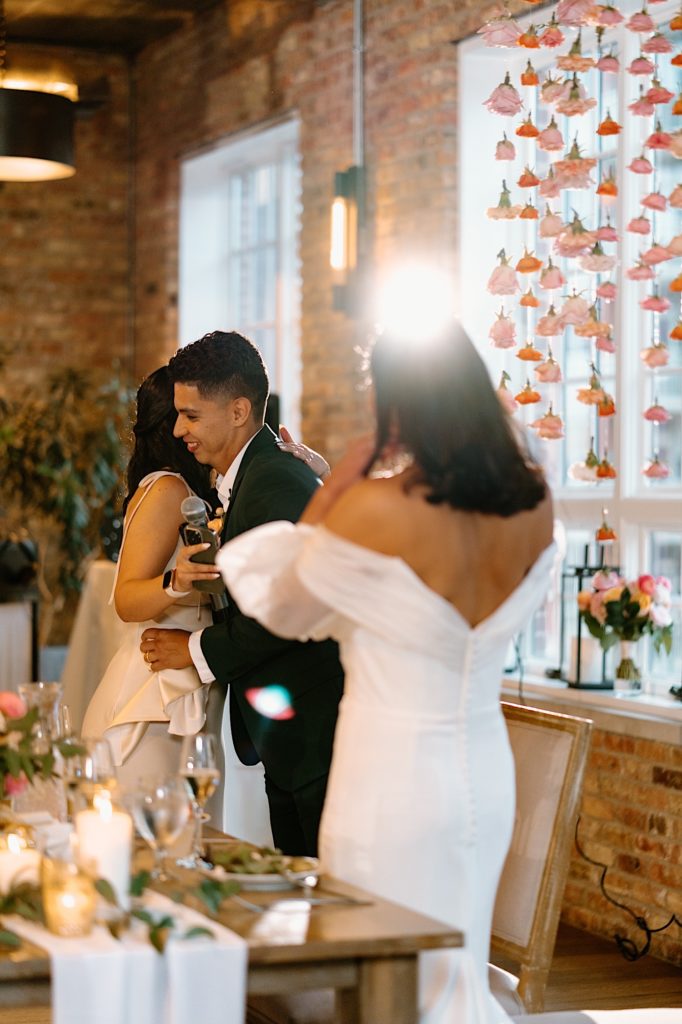 The groom hugs a bridesmaid after her speech at their intimate wedding in Chicago