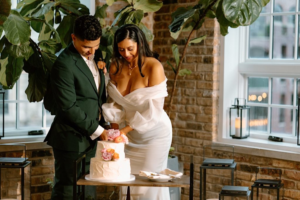 The bride and groom cut their wedding cake during their pink and orange themed wedding reception at Loft Lucia
