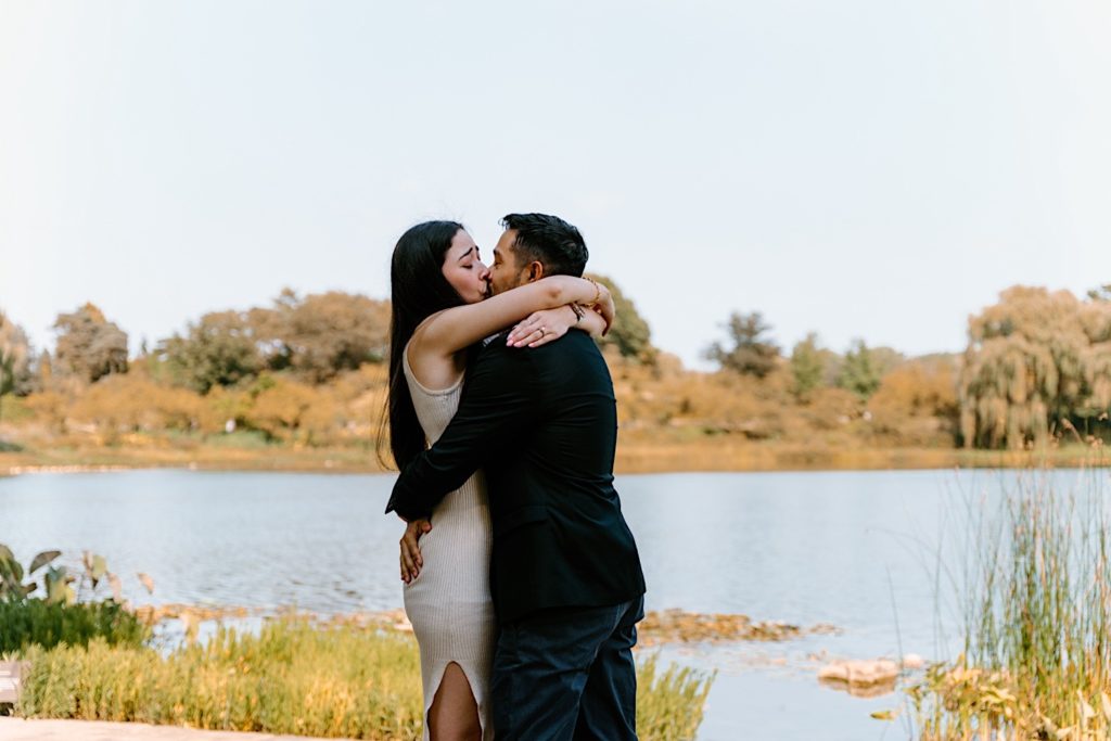 Fiancés kiss while holding one another at the Chicago Botanic Gardens