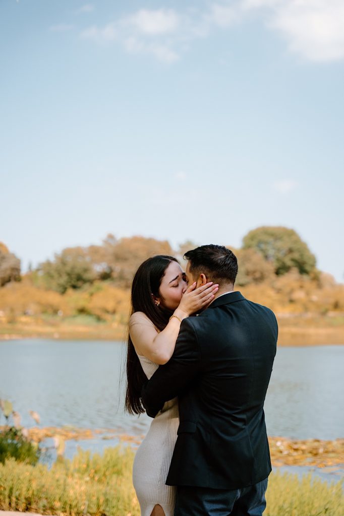 Fiancés kiss while holding one another at the Chicago Botanic Gardens