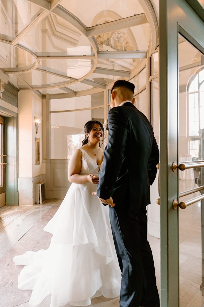 A bride and groom stand smiling at one another in the entrance space at Joliet's Union Station.