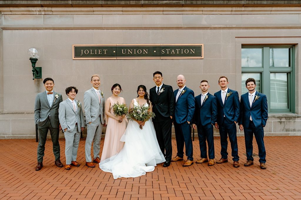 A wedding party stands outside of at Joliet's Union Station posing for portraits.
