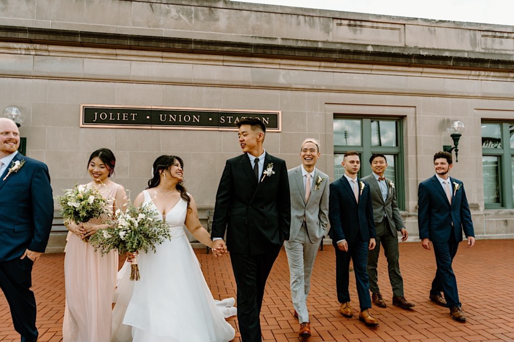 A wedding party walks outside of at Joliet's Union Station walking towards the camera for portraits.