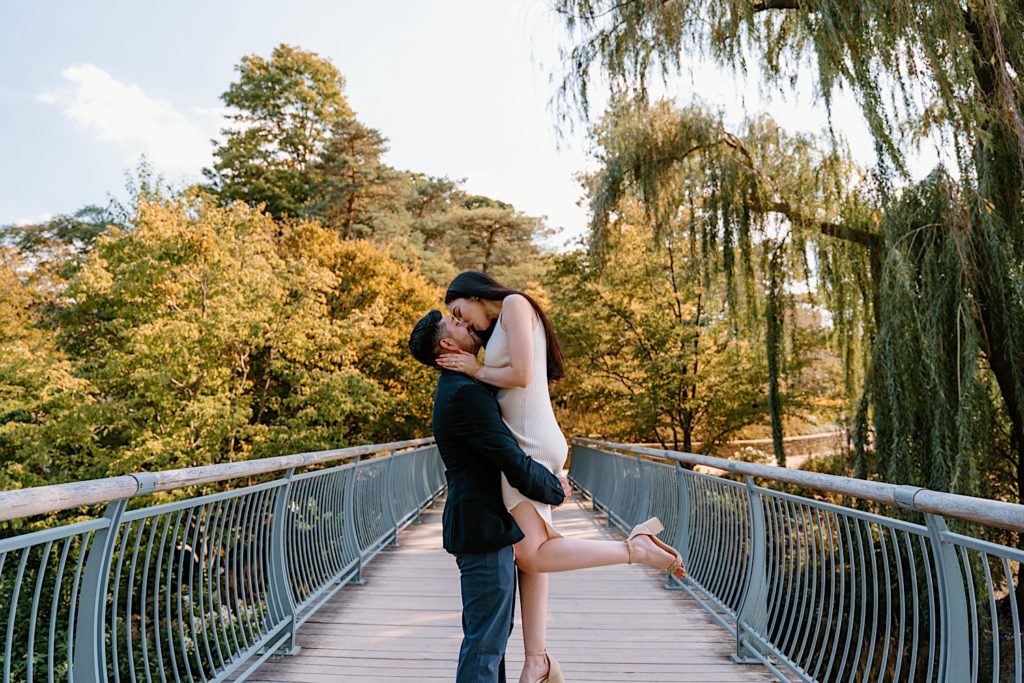 A couple holds one another while kissing on a bridge at the Chicago Botanic Gardens.
