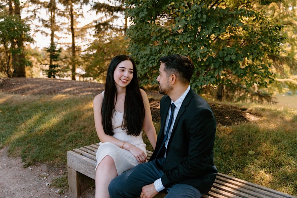 An engaged couple sits on a bench at the Chicago Botanic Gardens enjoying each others company