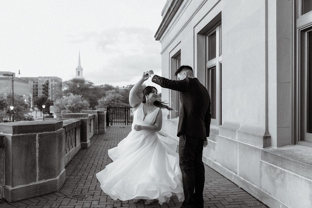 A groom twirls his bride on the balcony outside of Joliet Union Station on their wedding day.