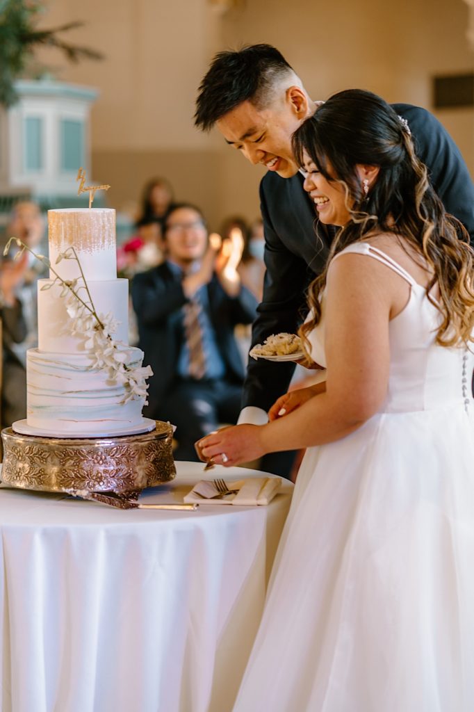 The bride and groom go to cut their cake at the reception at Joliet Union Station celebrating with their guests.