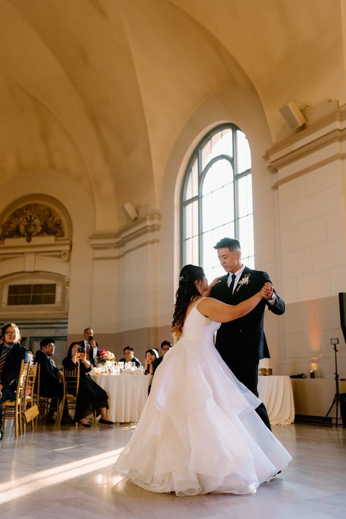 The bride and groom have their first dance at their wedding reception at Joliet Union Station celebrating with their guests.
