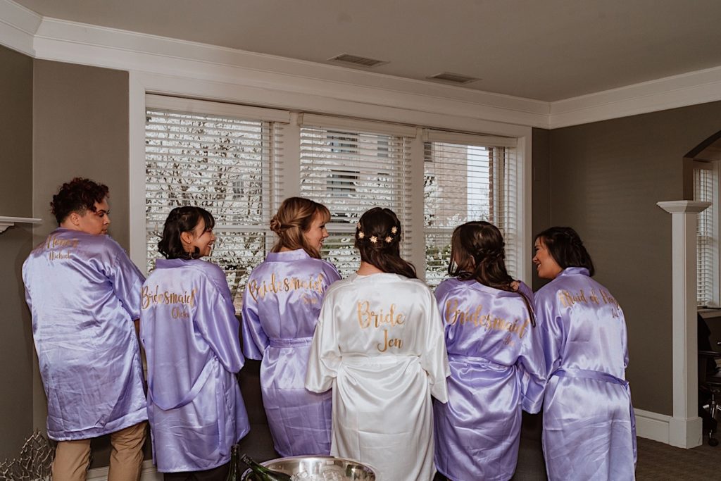 A bride and her bridesmaids wearing their custom lavender getting ready robes.  