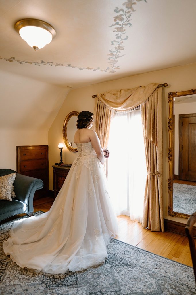 A bride standing in their wedding dress in the dressing room at the Redfield Estates.